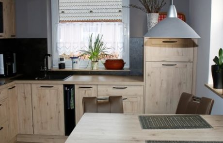 Küchenstudio Eine Küche mit Holzschränken und einem Tisch und Stühlen, die als Referenz dienen.
