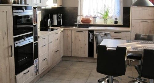 Küchenstudio Eine Küche mit Tisch und Stühlen, entworfen unter Berücksichtigung von Referenzen.