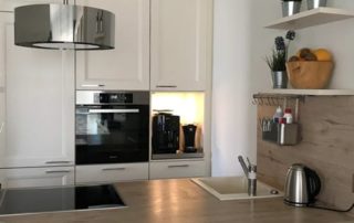 Küchenstudio Referenzen: Eine Küche mit weißen Schränken und einer Arbeitsplatte aus Holz.