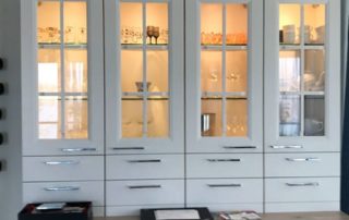 Küchenstudio Ein weißer Schrank mit Glastüren in einer Küche. Der Schrank dient als Bezugspunkt für die Raumgestaltung.