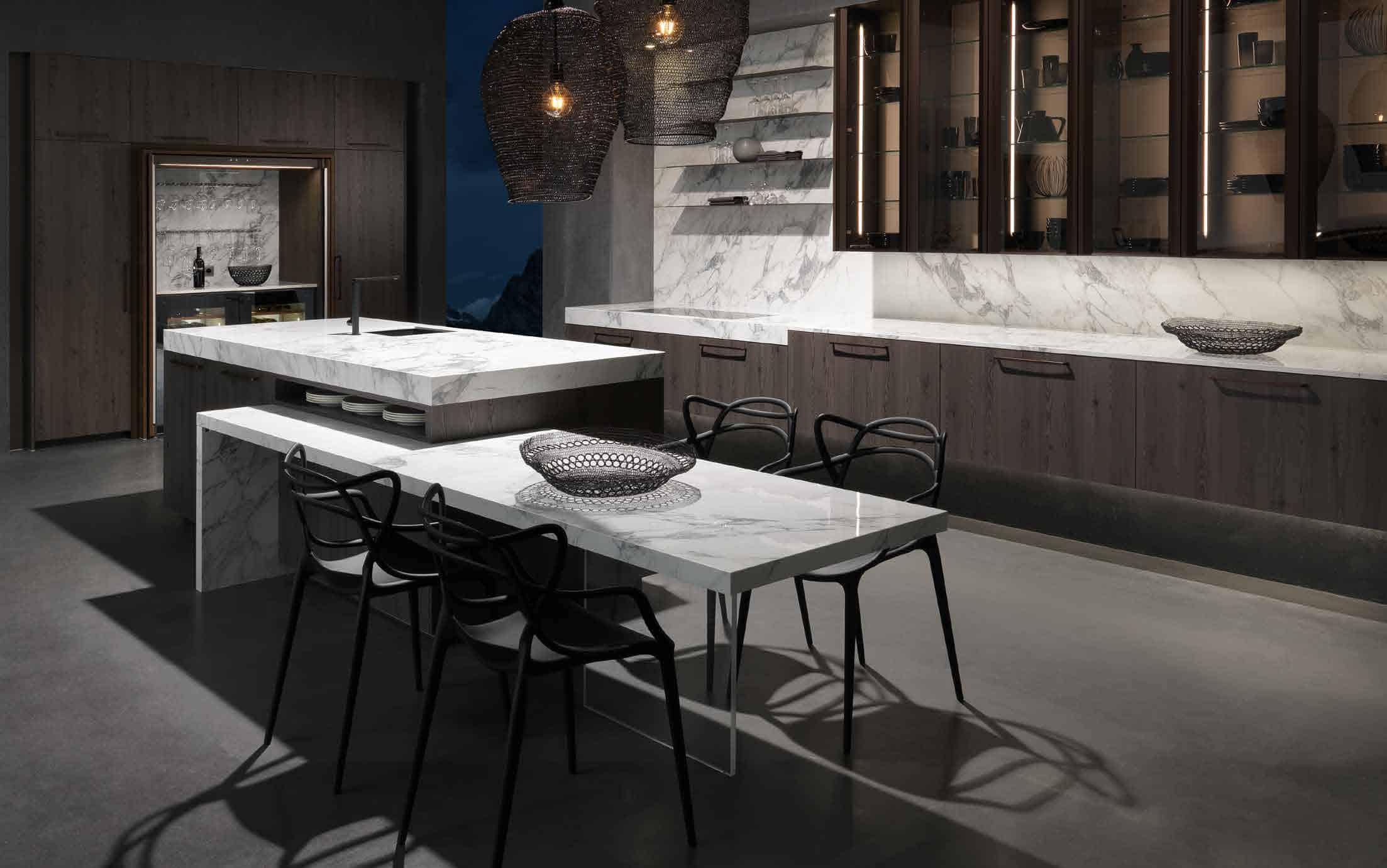 Küchenstudio Eine moderne Küche mit Marmoroberflächen und Stühlen.