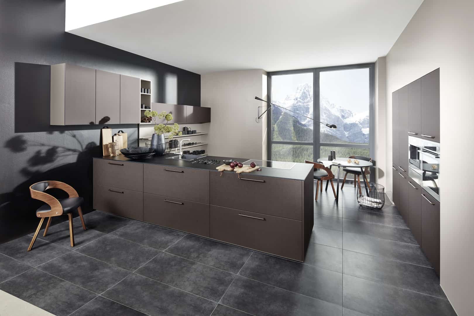 Küchenstudio Eine moderne Küche mit grauem Fliesenboden und Blick auf die Berge.