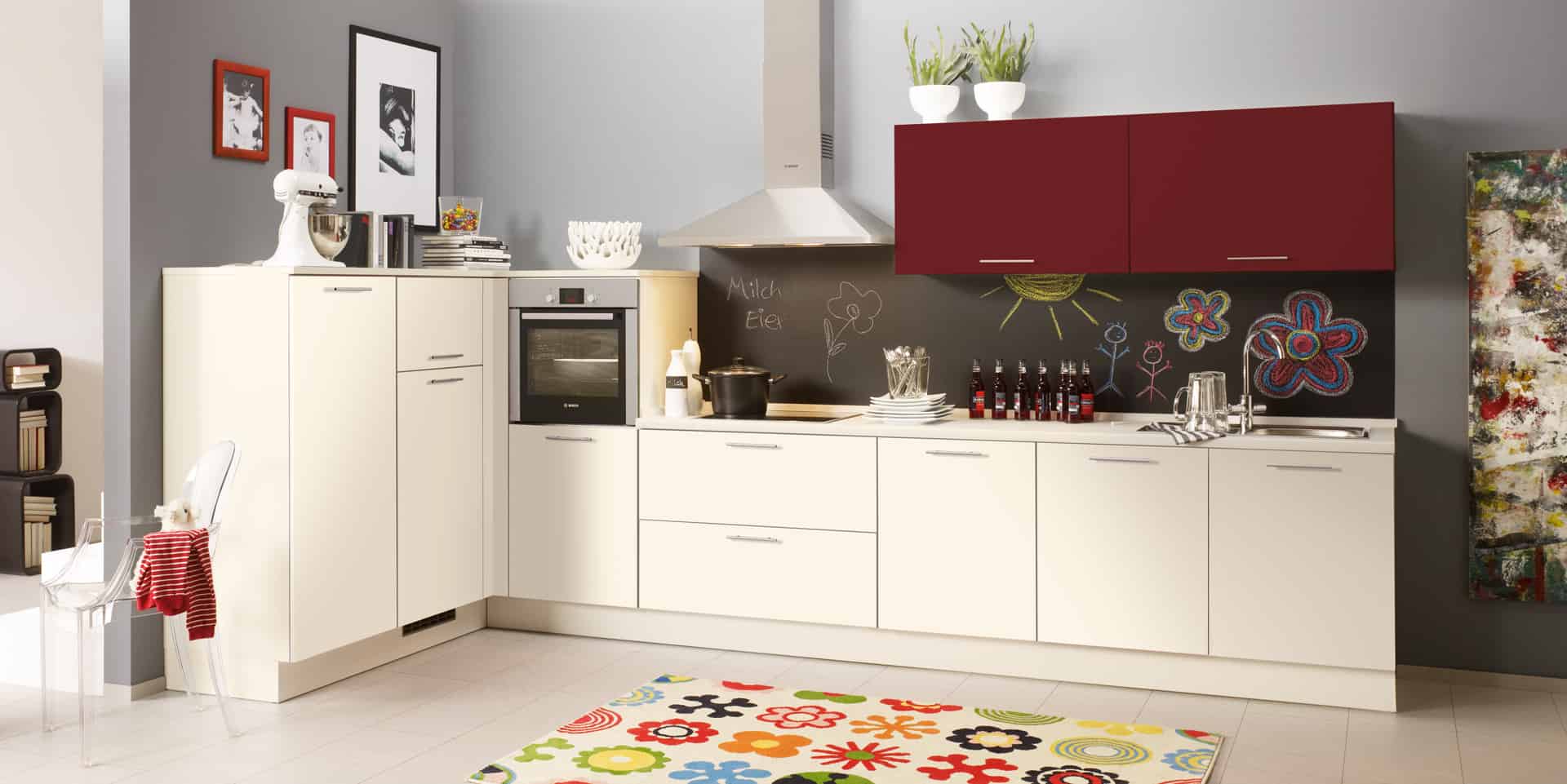 Küchenstudio Eine Küche mit weißen Schränken und einem roten Teppich.