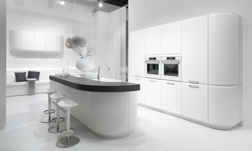 Küchenstudio Eine moderne Küche mit weißen Schränken und Hockern.