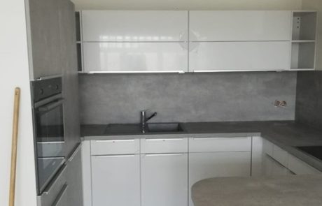 Küchenstudio Referenzen: Eine kleine Küche mit weißen Schränken und grauen Arbeitsplatten.