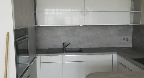 Küchenstudio Referenzen: Eine kleine Küche mit weißen Schränken und grauen Arbeitsplatten.