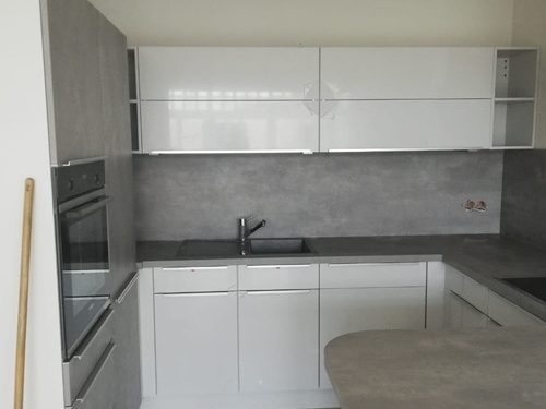 Küchenstudio Referenzen: Eine kleine Küche mit weißen Schränken und grauen Arbeitsplatten.