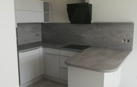 Küchenstudio Eine kleine Küche mit weißen Schränken und grauen Arbeitsplatten, perfekt für Ihre Referenzen.