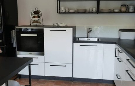 Küchenstudio Eine Küche mit weißen Schränken und schwarzen Arbeitsplatten im eleganten Referenzen-Design.