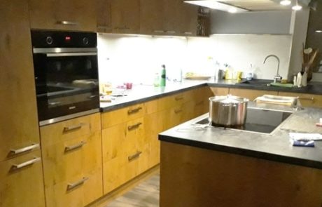 Küchenstudio Eine Küche mit Holzschränken und einem Herd, die exquisite Referenzen präsentiert.