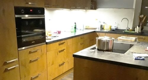 Küchenstudio Eine Küche mit Holzschränken und einem Herd, die exquisite Referenzen präsentiert.