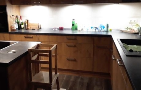 Küchenstudio Eine Küche mit schwarzen Schränken und einem Hocker. (Referenzen)