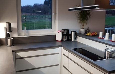Küchenstudio Referenzen: Eine Küche mit weißen Schränken und einem Fenster, die unser Fachwissen bei der Gestaltung eleganter und schöner Wohnräume unterstreicht.