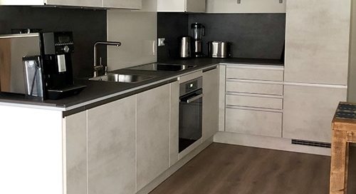 Küchenstudio Referenzen: Eine Küche mit weißen Schränken und Holzböden.