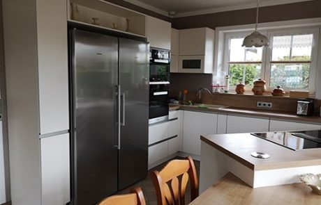 Küchenstudio Eine Küche mit Tisch und Stühlen sowie einem Kühlschrank, die auf einen gemütlichen Essbereich verweist.