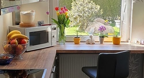 Küchenstudio Eine Küche mit einer Mikrowelle und einem Fenster.