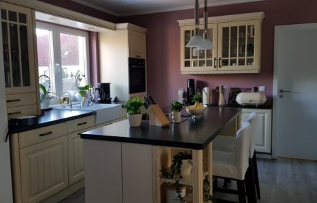 Küchenstudio Eine Küche mit lila Wänden und schwarzen Arbeitsplatten, gefüllt mit eleganten Referenzen.