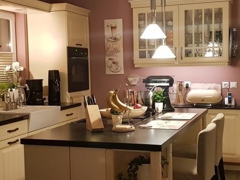 Küchenstudio Eine Küche mit lila Wänden und schwarzen Arbeitsplatten, inspiriert von modernem Design und mit exquisitem Geschmack dekoriert.