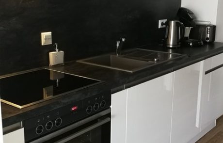 Küchenstudio Referenzen: Eine elegante und moderne Schwarz-Weiß-Küche mit einem hochmodernen Herd und Backofen.