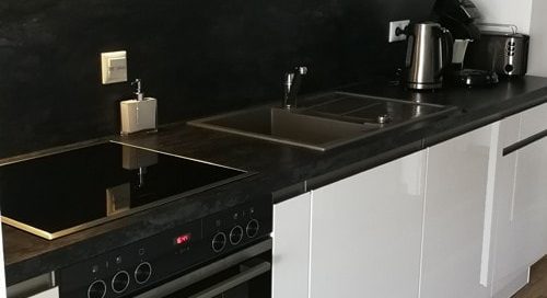 Küchenstudio Referenzen: Eine elegante und moderne Schwarz-Weiß-Küche mit einem hochmodernen Herd und Backofen.