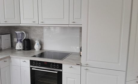 Küchenstudio Eine Küche mit weißen Schränken und Referenzen zu einem Mikrowellenherd.