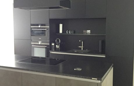 Küchenstudio Referenzen: Eine Küche mit schwarzen Schränken und einer schwarzen Insel.