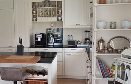 Küchenstudio Eine weiße Küche mit Barhockern und Regalen, die als Referenzen dienen.