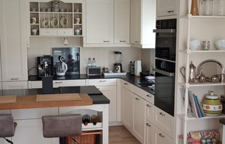 Küchenstudio Referenzen: Eine Küche mit weißen Schränken und einem Barbereich.
