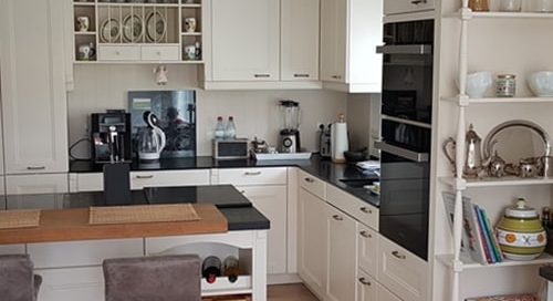 Küchenstudio Referenzen: Eine Küche mit weißen Schränken und einem Barbereich.