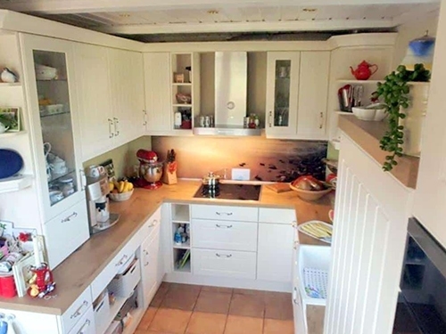 Küchenstudio Referenzen: Eine Küche mit weißen Schränken und Holzboden.