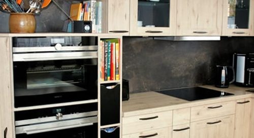 Küchenstudio Eine Küche mit Holzschränken und einer Mikrowelle. Die Holzschränke und der Mikrowellenherd sind hochwertige Referenzen für dieses moderne Küchendesign.