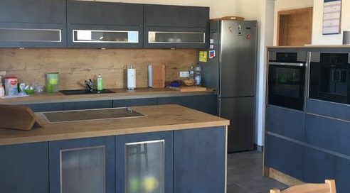 Küchenstudio Referenzen: Eine Küche mit blauen Schränken und Holzarbeitsplatten.