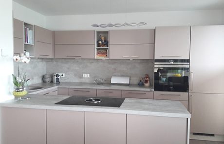 Küchenstudio Eine Küche mit weißer Arbeitsplatte und grauen Schränken.