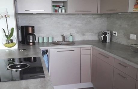 Küchenstudio Eine kleine Küche mit grauen Schränken und einer Mikrowelle.