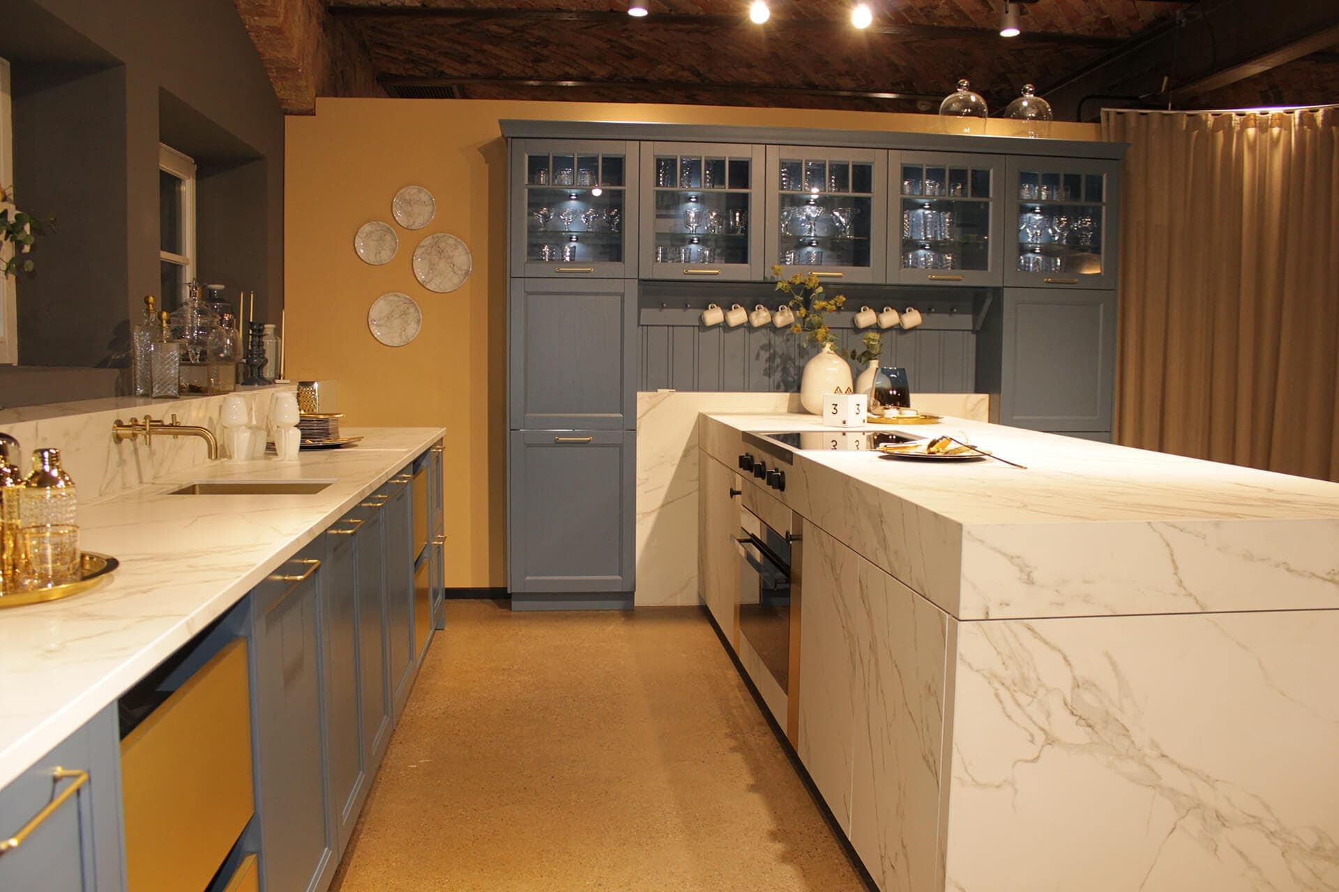 Küchenstudio Eine Küche mit blauen Schränken und Marmorarbeitsplatten.