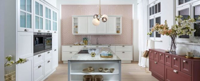 Küchenstudio Eine Küche mit weißen Schränken und einer rosa Kücheninsel.