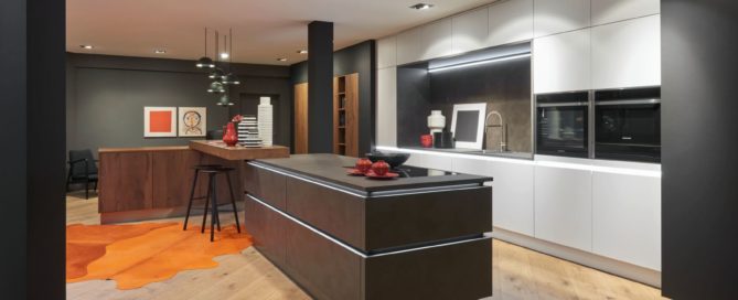 Küchenstudio Eine moderne Küche mit Holzböden und orangefarbenen Teppichen.
