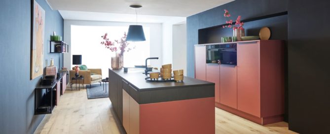 Küchenstudio Eine Küche mit einer roten Insel und schwarzen Wänden.