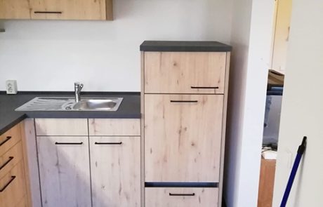 Küchenstudio Eine kleine Küche mit Holzschränken und einer Spüle.