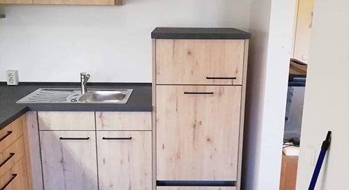 Küchenstudio Eine kleine Küche mit Holzschränken und einer Spüle.