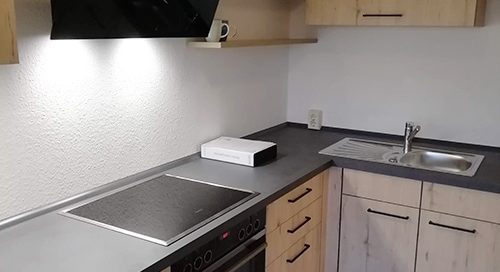 Küchenstudio Eine kleine Küche mit Holzschränken und einer Mikrowelle.