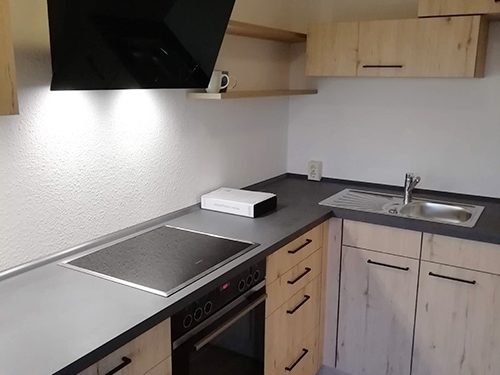 Küchenstudio Eine kleine Küche mit Holzschränken und einer Mikrowelle.
