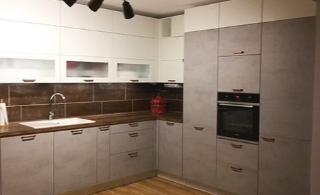 Küchenstudio Eine Küche mit grauen Schränken und Holzböden.