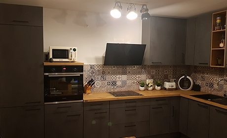 Küchenstudio Eine Küche mit grauen Schränken und einer Mikrowelle.