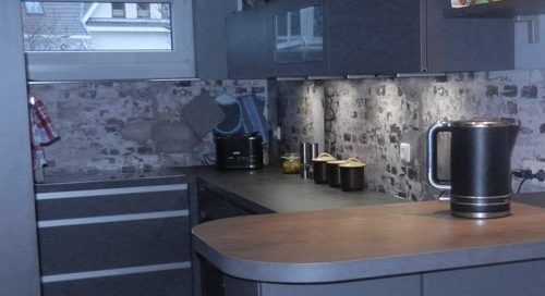 Küchenstudio Eine graue Küche mit Herd und Spüle.