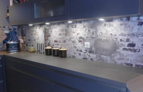Küchenstudio Eine blaue Küche mit einer Backsteinmauer.