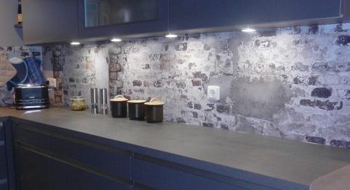 Küchenstudio Eine blaue Küche mit einer Backsteinmauer.