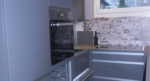 Küchenstudio Eine graue Küche mit Geschirrspüler und Backofen.