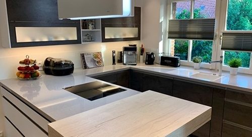 Küchenstudio Eine moderne Küche mit weißen Arbeitsplatten und Holzschränken.