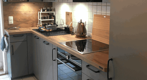 Küchenstudio Eine kleine Küche mit Herd, Backofen und Referenzen.